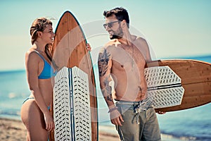 Attractive man and woman outdoors - surfers on the beach