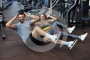 Attractive man and woman working in pairs performing sit ups in gym