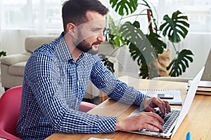 Attractive man working in laptop while sitting in red armchair