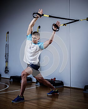 Attractive man during workout with suspension straps In The Gym