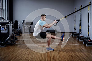 Attractive man during workout with suspension straps In The Gym photo