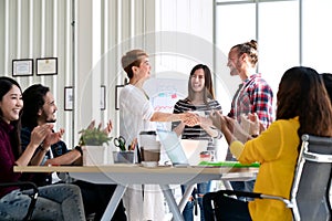 Attractive mature asian woman shaking hand with young beard hipster caucasian with welcome new employee