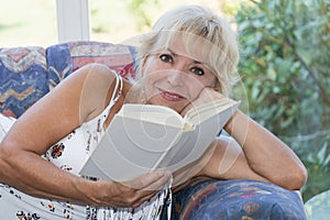 Attractive mature blond woman is reading a book