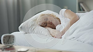 Attractive mature female sleeping in her bed, rest at home, healthy lifestyle