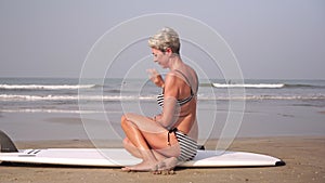 Attractive mature senior woman surfing and outdoor activities on the beach