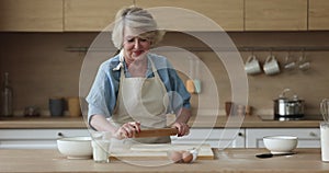 Attractive mature woman flattening dough for pie or cake