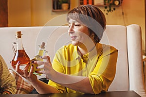 Attractive mature woman holding olive oil and balsamic vinegar bottles in italian trattoria