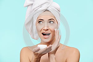 Attractive mid 30s woman applying moisturizer cream on her face. Photo of attractive caucasian woman with healthy skin.