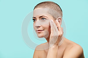 Attractive mid 30s woman looking at herself in the mirror, touching her temples and pulling skin back. Young woman with wrinkles.