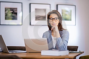 Attractive mid aged woman sitting at home and using laptops for work