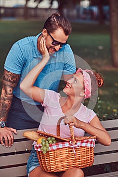 Attractive middle age couple during dating, enjoying a picnic on a bench in the city park.