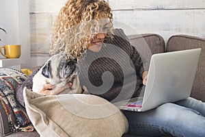 Attractive middle age woman with her best friend old dog pug working together on a laptop at home - watching movie on computer and