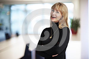 Attractive middle aged businesswoman looking at camera and smiling while standing in the boardroom