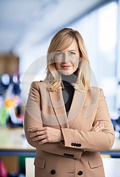 Attractive middle aged businesswoman looking at camera and smiling while standing at the office