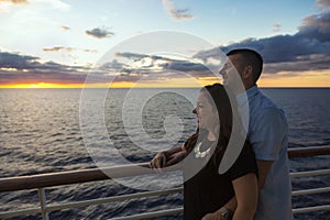 Attractive middle-aged couple enjoying the sunset view from the deck of a cruise ship