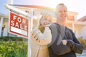 Attractive Middle-aged Couple In Front House and For Sale Real Estate Sign