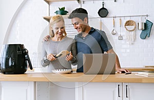 Attractive middle aged couple on kitchen. Beautiful woman is coo
