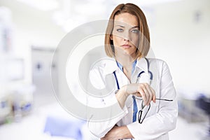 Attractive middle aged female doctor standing in doctor`s room photo