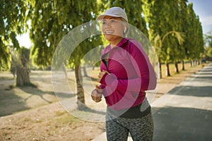 Attractive middle aged lady running happy at city park . beautiful and sporty woman on her 40s exercising doing jogging workout on