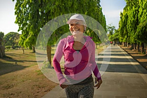 Attractive middle aged lady running happy at city park . beautiful and sporty woman on her 40s exercising doing jogging workout on