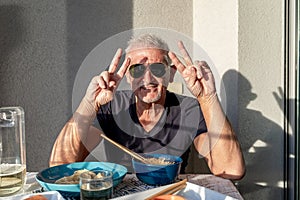 attractive middle-aged man have fun while eating sitting at a table laid Chinese take away food