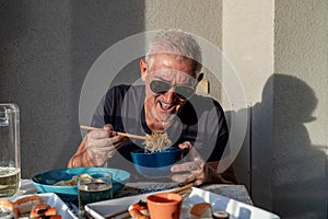 attractive middle-aged man have fun while eating sitting at a table laid Chinese take away food