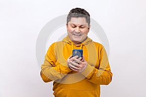 Attractive middle aged man using mobile phone with happy expression, addicted to smartphone.