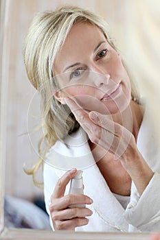 Attractive middle-aged woman applying cosmetics