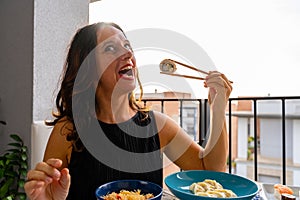 Attractive middle-aged woman eating Chinese take away food sitting at a laid table