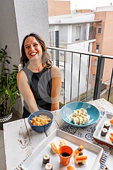 Attractive middle-aged woman eating Chinese take away food sitting at a laid table