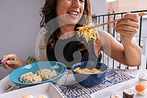 Attractive middle-aged woman eating Chinese take away food sitting at a laid table