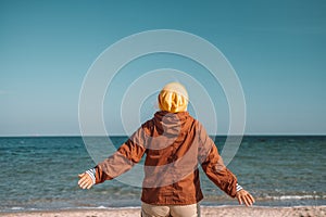 Happy woman enjoying freedom with open hands on sea. Enjoying travel and nature concept