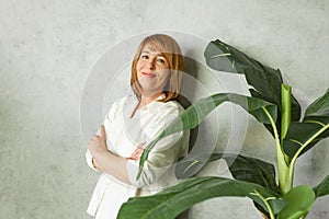 Attractive middle-aged woman on a gray background in a white blouse