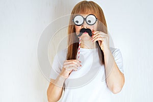 Attractive middle aged woman having fun with a fake moustache and glasses.