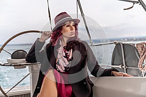 Attractive middle-aged woman at the helm of a yacht on a summer day. Luxury summer adventure, outdoor activities.
