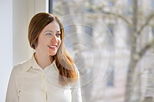 Attractive middle-aged woman with long auburn hair looking aside