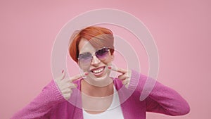 Attractive middle aged woman with red hair pointing fingers on her white teeth