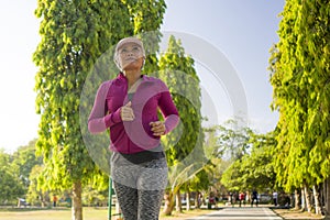 Attractive middle aged woman running happy at city park . beautiful and sporty lady on her 40s exercising doing jogging workout on