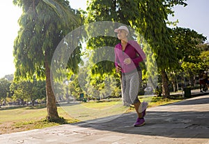 Attractive middle aged woman running happy at city park . beautiful and sporty lady on her 40s exercising doing jogging workout on