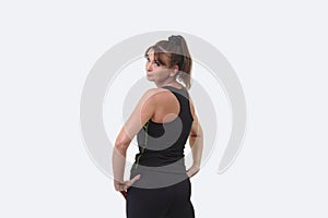 Attractive middle-aged woman in sports gear with back to camera turning to smile