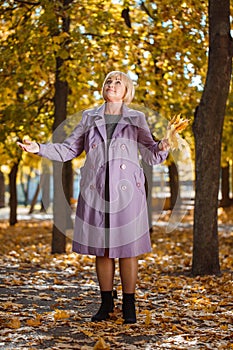 An attractive middle-aged woman walking in an autumn park on a blurred background.