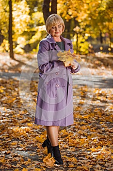 An attractive middle-aged woman walking in an autumn park on a blurred background.