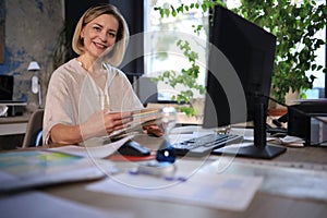 Attractive middle aged woman working at office, using contemporary desktop computer.