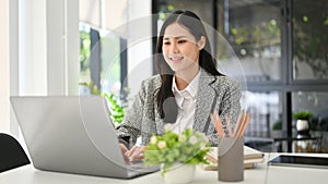 Attractive millennial Asian businesswoman working in her office, using laptop computer