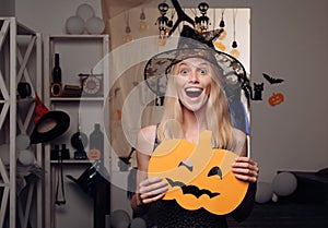 Attractive model girl in Halloween costume. Halloween Witch with pumpkin. Beautiful young woman in black witch costume