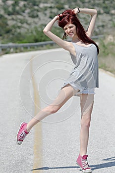 Attractive model standing in the middle of a mountain road