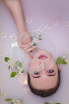 An attractive model takes a bath with milk and apple petals.