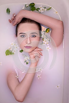 An attractive model takes a bath with milk and apple petals.