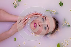 An attractive model takes a bath with milk and apple petals.