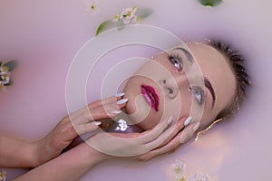 An attractive model takes a bath with milk and apple petals.